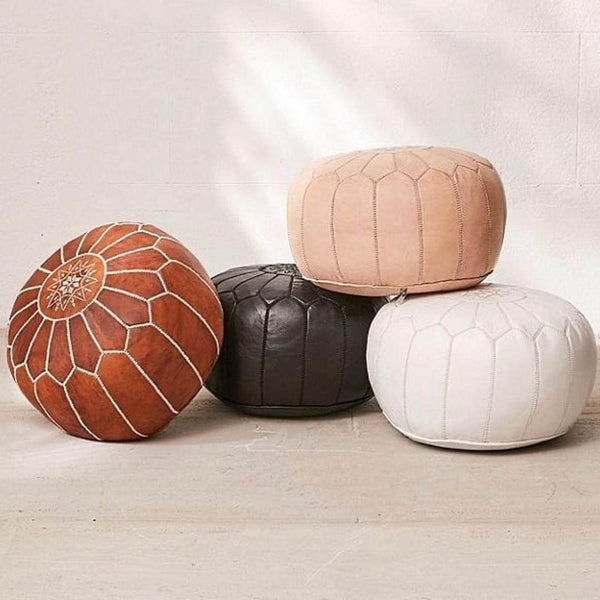 Tan brown Moroccan leather ottoman pouffe, handmade and embroidered, displayed with other pouffes.